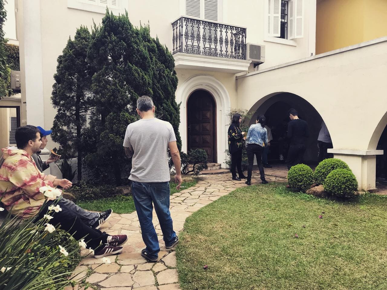 A group of people standing around in front of a house.
