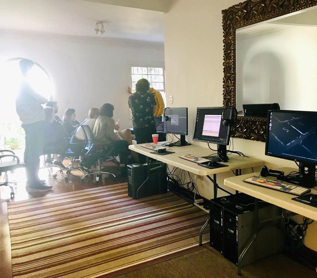 A room with two computers and people sitting in chairs.